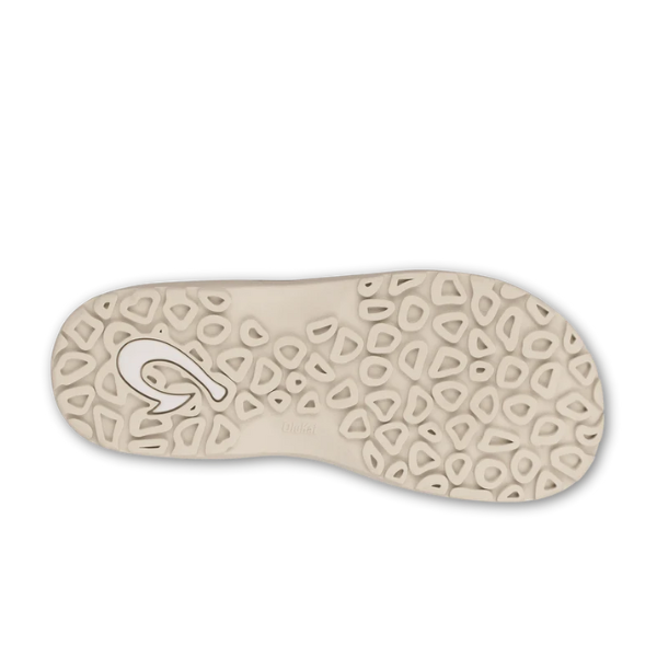 The image shows the sole of the OLUKAI Mens Ohana sandal in Deep Blue/White, with a light beige color, an irregular textured pattern of raised pebble-shaped grips, and a stylized logo embedded near the heel.