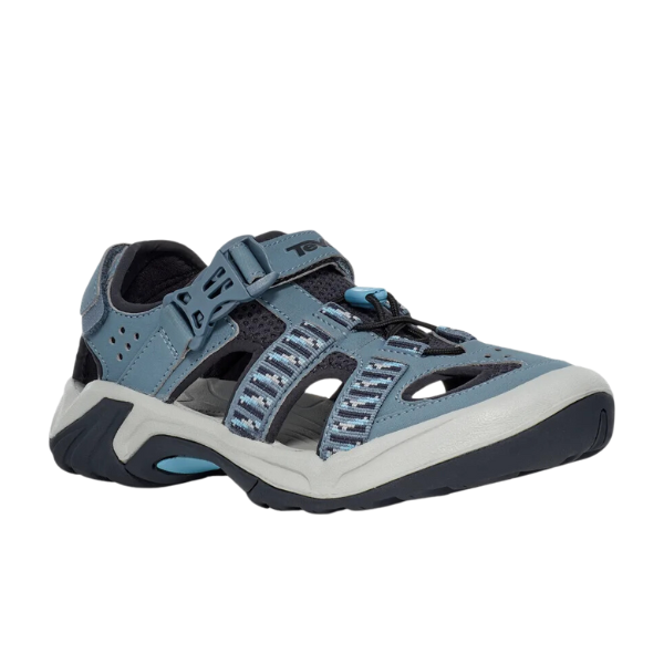 The Teva Womens Omnium 2 Hybrid Blue Mirage features a quick-drying blue and gray upper, closed toe, perforated sides, secure Velcro strap, rugged black sole, and patterned fabric accents for style and durability.