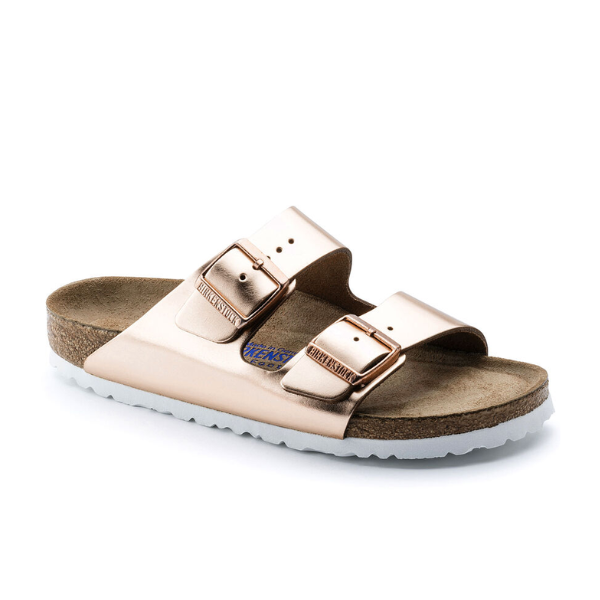 The BIRKENSTOCK Womens Arizona Soft Footbed Leather White Copper sandal features a soft cork footbed, ergonomic insole with Birkenstock logo, and two adjustable metallic copper straps.