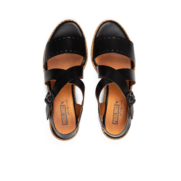 The Pikolinos Womens Blanes Heeled Sandals in black feature punched leather, tan soles, and cross-over straps. Branded insoles show the PIKOLINOS logo. Designed for stylish comfort and shown from above on a white background.
