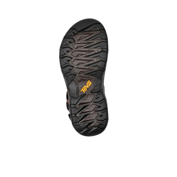 The image shows the black sole of a Teva Mens Terra Fi 5 Universal Leather Turkish Coffee sandal, featuring a rugged zigzag tread and a yellow Teva logo in the center, all set against a plain white background.