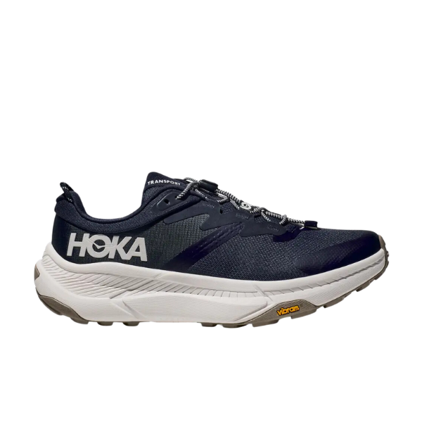 The HOKA Mens Transport Wide Navy athletic shoe features a navy finish, white sole, white HOKA logo, VIBRAM outsole, quick-lace system, rugged tread, and vegan materials—ideal for running or outdoor activities.