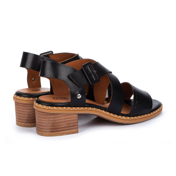 The PIKOLINOS Womens Blanes Heeled Sandals in black feature punched leather, medium brown block heels, buckle closures, and white stitching around the sole, shown against a white background.