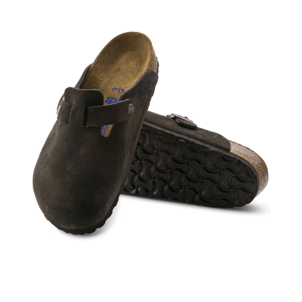 A pair of BIRKENSTOCK Womens Boston Soft Footbed Suede Leather clogs in mocha, featuring cork soles and adjustable side buckles; one shoe is flat while the other displays its textured rubber sole.