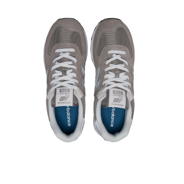 Top view of New Balance Mens 574 Core Neutral shoes in gray with white laces, white midsoles, and navy blue insoles. Features NEW BALANCE branding on the tongue and insole—versatile footwear for any occasion.