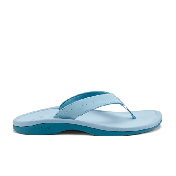 The OLUKAI Womens Ohana Misty Blue sandal, shown from the side on a white background, features a light blue strap, darker blue sole, and a comfort footbed.