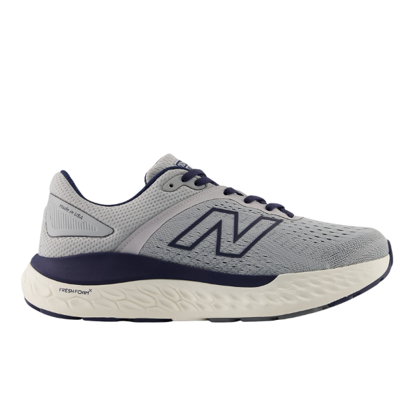 The New Balance Mens Fresh Foam X 1540v4 Wide in Grey/White features a light gray design with a navy N logo, navy trim, and a white textured sole equipped with Fresh Foam X cushioning for comfort and support.