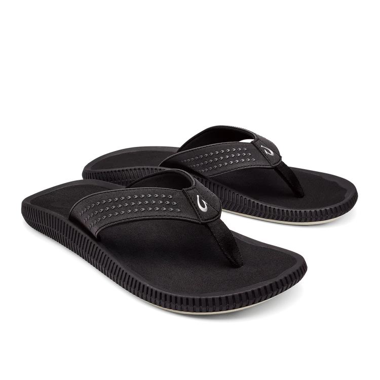 A pair of OLUKAI Mens Ulele Black water-resistant sandals with textured soles and stitched strap details, designed for foot pain comfort, shown on a white background.