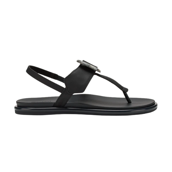 The OLUKAI Olukai Womens La‘i T–Bar Lava Rock is a black leather T-Bar sandal with a round buckle, ankle strap, and flat sole, shown in side view on white. Perfect stylish footwear for those seeking plantar fasciitis support.