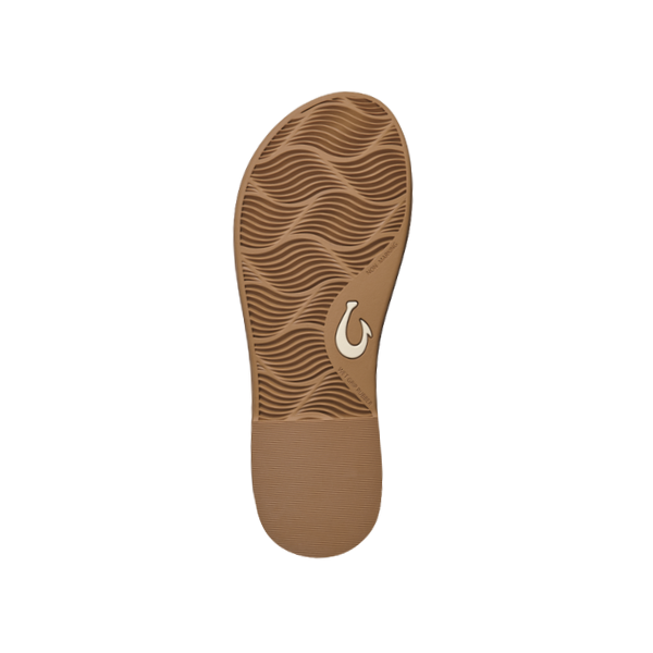 The OLUKAI Womens La‘i T–Bar Tan features a brown sandal sole with a wavy tread and a white hook-shaped logo, designed for foot pain relief—combining comfort and style against a crisp white background.