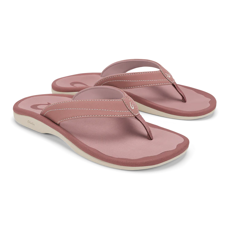 A pair of OLUKAI Womens Ohana Coral Rose flip-flops with thick straps, anatomical footbed, and white soles is displayed on a plain background.