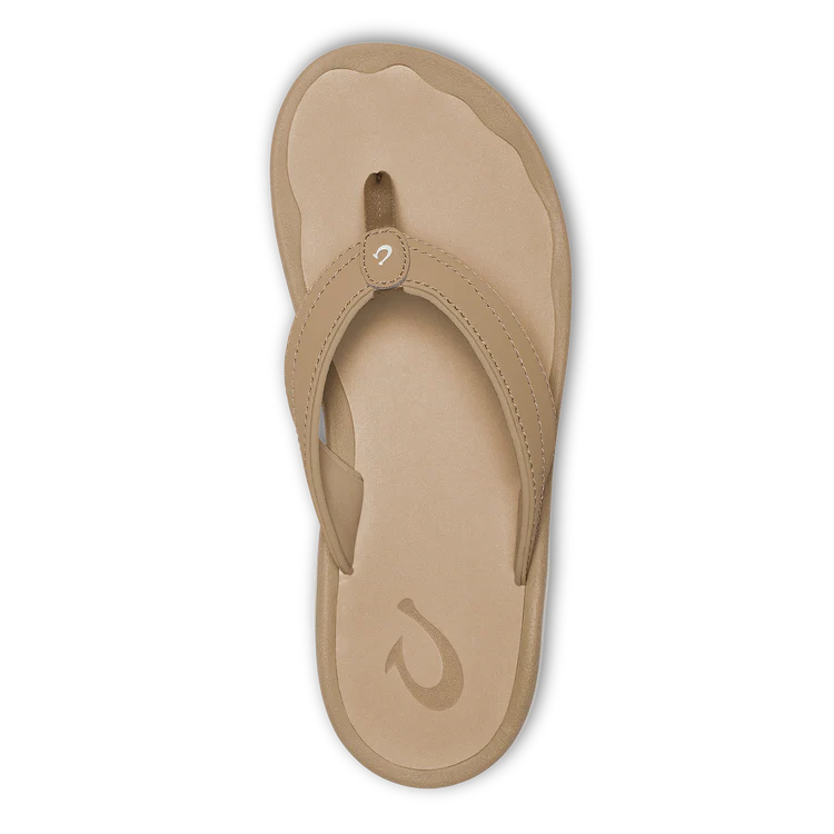 OLUKAI Womens Ohana Warm Sand sandal with thick straps and a textured anatomical footbed, shown from above on a black background.