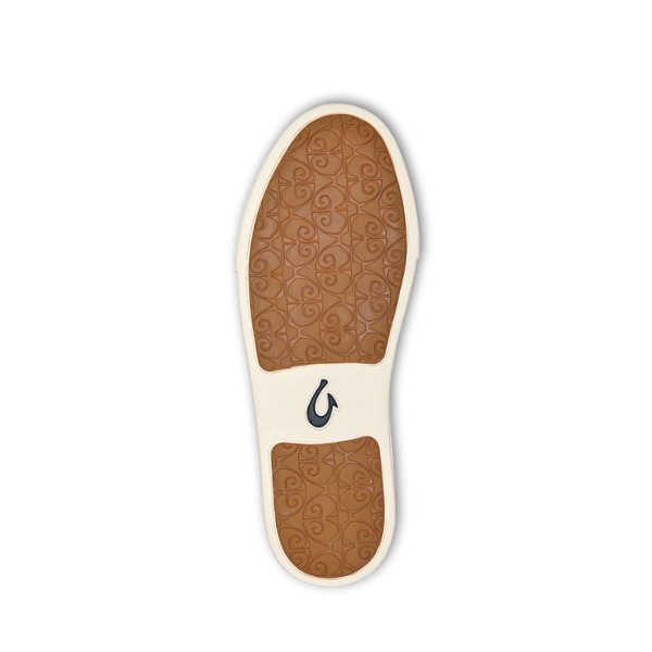 A brown shoe sole with an intricate swirl pattern and a black wave-like OLUKAI logo highlights the comfort of the Olukai Womens Pehuea Lī ‘Ili Leather White sneakers, set against a white background.