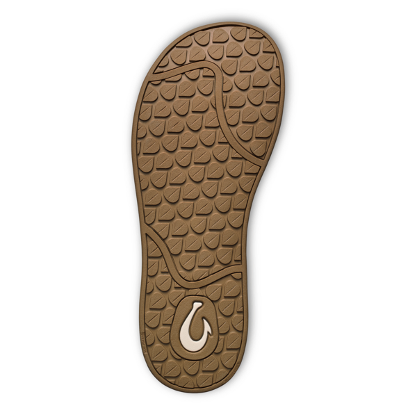 The image shows the sole of the OLUKAI Womens Southshore Toffee sandal, featuring a textured brown surface with a leaf pattern, a white fish hook design by the heel, and a black-edged Wet Grip Rubber® outsole.