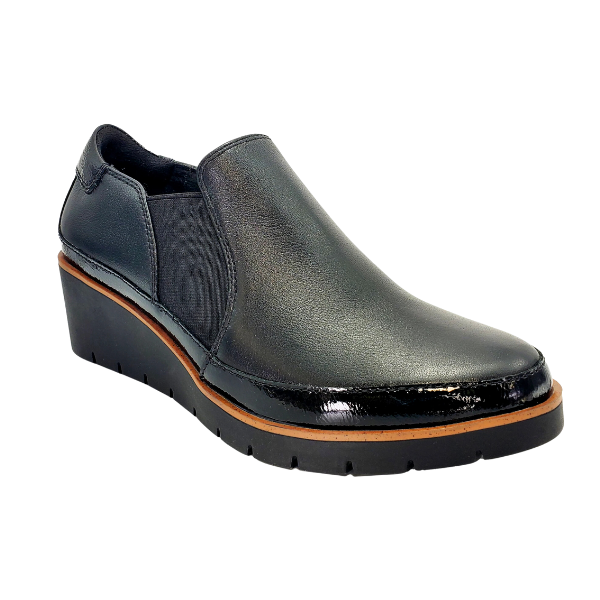 The REVERE Revere Womens Mykonos Wedge Loafer Black features a shiny slip-on design, elastic side panel, brown accent above the sole, and ridged outsole—ideal for plantar fasciitis or stylish travel.