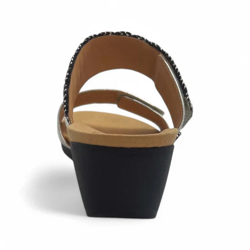 A rear view of the Revere Womens Sorrento Silver open-toe wedge sandal by REVERE, featuring a tan footbed, black low wedge heel, and decorative strap—ideal support for plantar fasciitis; photographed on a white background.