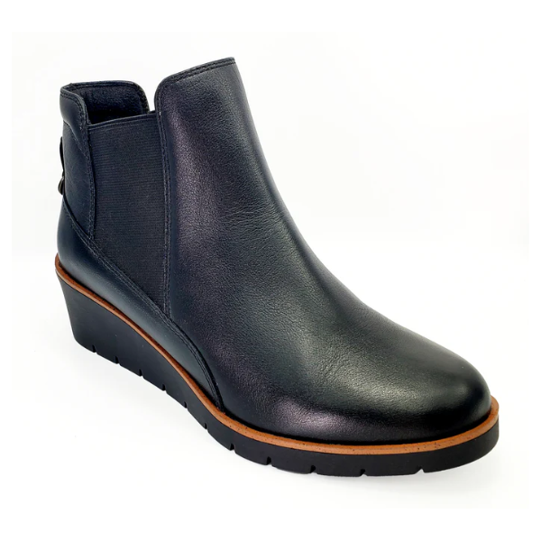The REVERE Reverse Womens Galway Wedge Bootie Wide in black features a premium leather upper, low wedge heel, brown trim around the sole, and elastic side panels, shown on a white background.