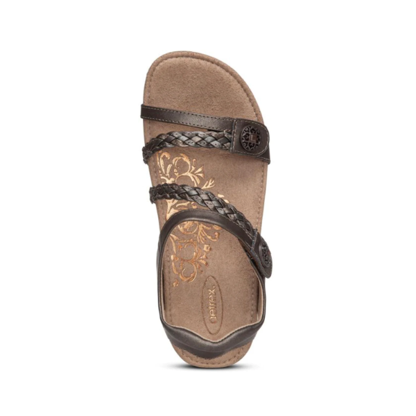 The Aetrex Womens Jillian Bronze sandal features braided and smooth straps, a floral tan Lynco orthotic footbed, and a circular decorative emblem near the straps, displayed against a white background.