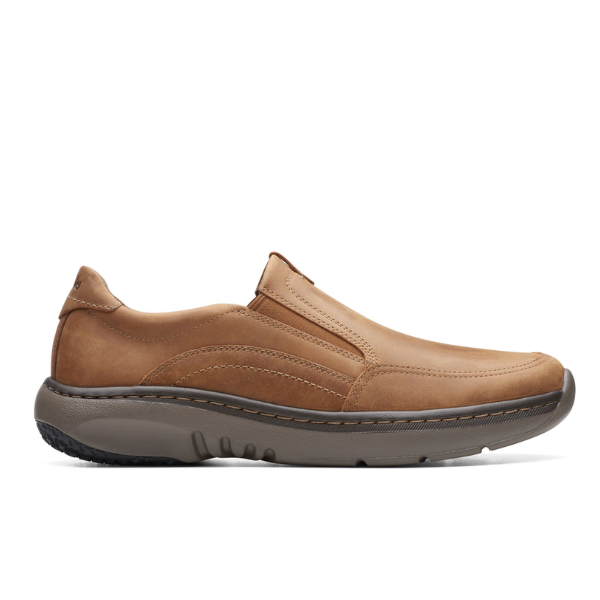 The Clarks Mens Pro Step Beeswax Leather slip-on features visible stitching, a rounded toe, a thick textured gray rubber sole, slip-resistant grip, and a removable insole for casual everyday comfort.