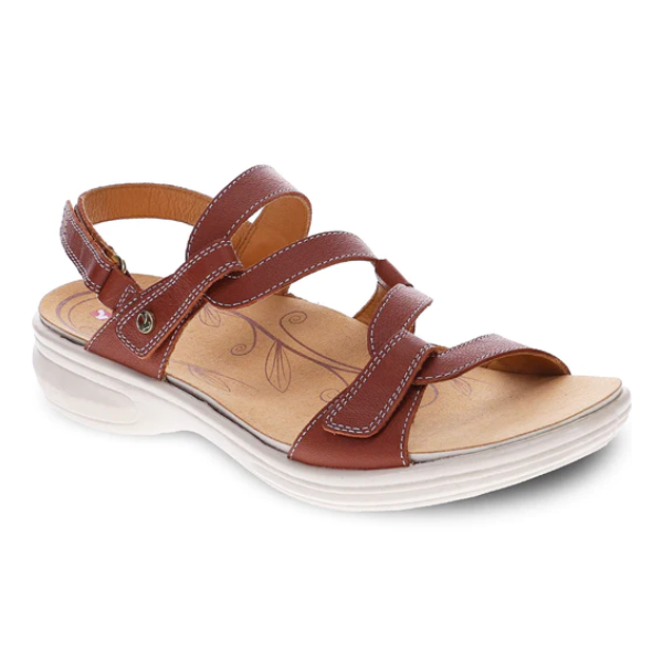 The REVERE Revere Womens Emerald Cognac sandal features luxe brown leather, three adjustable straps, decorative stitching, a cushioned beige floral-patterned footbed, and a white slightly elevated sole with open-toe design.