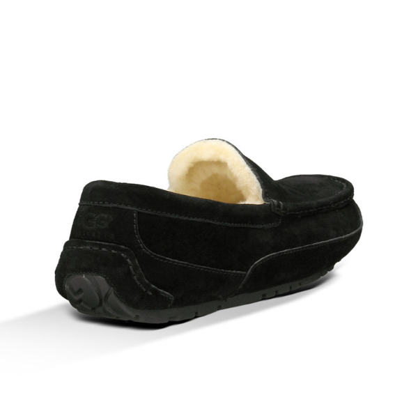 The UGG Mens Ascot Slipper Black features black suede, a rubber sole, and a cream fluffy lining for comfort. Designed by UGG as a loafer-style slipper, it’s shown from the back and side angles.