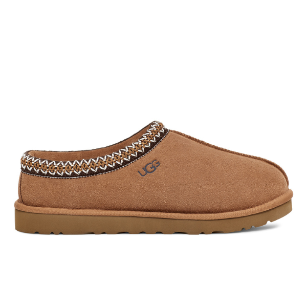 The UGG Mens Tasman Slipper Chestnut features brown suede, a light brown durable outsole, decorative stitching on the collar, the UGG logo on the side, and provides both style and foot pain comfort.