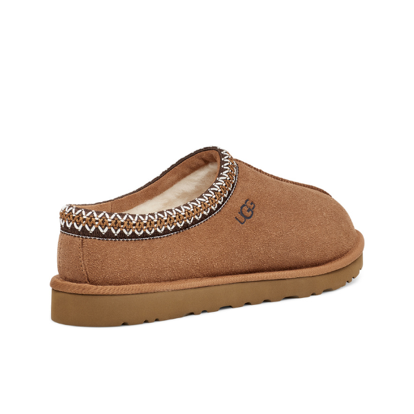The UGG Mens Tasman Slipper Chestnut features cozy shearling lining, decorative stitching, UGG logo, and a durable outsole for max comfort, shown from the back.
