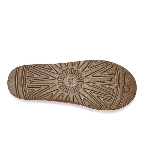 The UGG Mens Tasman Slipper in Chestnut features a brown rubber sole with a textured geometric pattern, UGG branding at the center, grooves for traction, and a circular heel design for durable comfort.