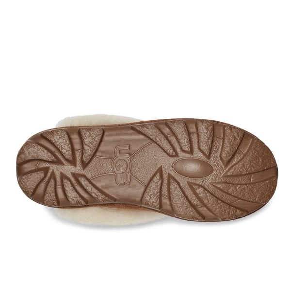 The image shows the brown rubber sole of the UGG Womens Coquette Slipper Chestnut, featuring a textured tread and central UGG logo, with cream sheepskin lining visible along the edge.