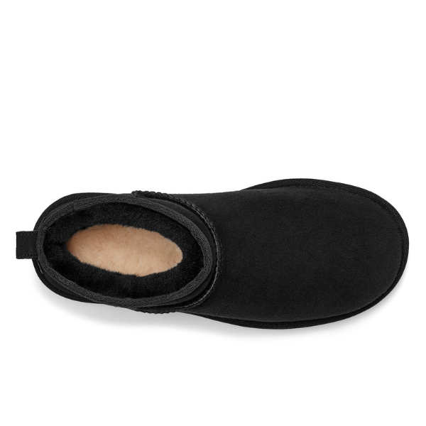 Top view of the UGG Womens Classic Ultra Mini Boot Black shows its rounded toe, black suede exterior with matching stitching, and visible soft beige sheepskin fleece lining inside.