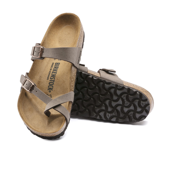 A pair of BIRKENSTOCK Womens Mayari Birkibuc Mocha sandals is shown: one sandal upright displays the cork footbed and mocha Birkibuc straps with buckles, while the other is tilted to show the black textured sole.