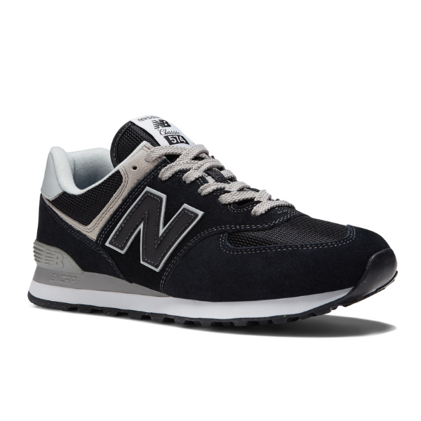 The New Balance Unisex 574 Black with White features a black and gray design, white accents and laces, a large N logo, black outsole, and is crafted by NEW BALANCE to help reduce foot pain during everyday wear.