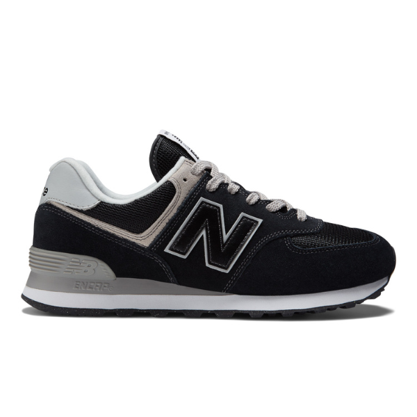 The New Balance Unisex 574 Black with White features a black and gray design, white N logo, gray heel, and white laces, shown side profile on a white background. Stylish and comfy by NEW BALANCE—great for those worried about foot pain.