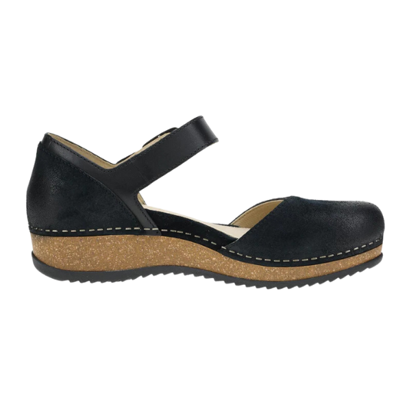 The Dansko Womens Mae Black Suede shoe features a closed toe, ankle strap, cork-textured wedge sole, and white stitching for stylish comfort and foot pain relief.