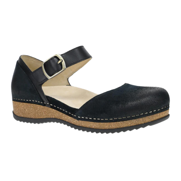 The Dansko Womens Mae Black Suede by DANSKO features a closed-toe black suede Mary Jane design with an ankle strap and buckle, cushioned beige insole for comfort, and a low brown wedge heel with visible stitching on the sole.