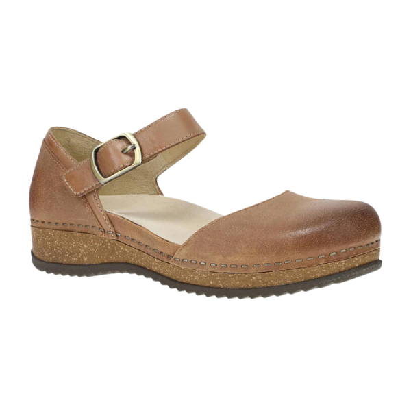 The Dansko Womens Mae Tan Suede by DANSKO is a brown suede Mary Jane with a low wedge heel, ankle strap with buckle, visible stitching, lightweight EVA and cork midsoles for comfort, and a textured rubber outsole.