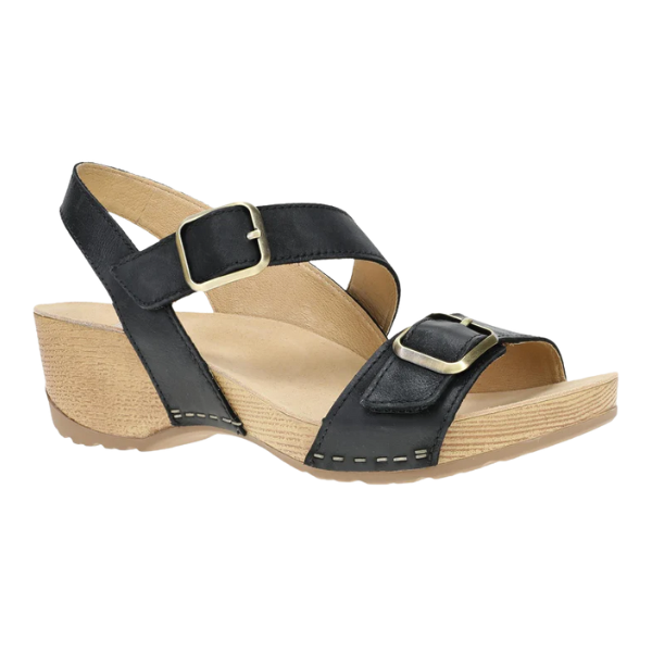 The Dansko Womens Trinity Black Burnished Nubuck sandal by DANSKO features a beige wedge heel, open toe, two adjustable buckle straps, visible sole stitching, and a contoured footbed for arch support.