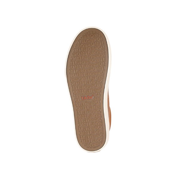 The image displays the bottom sole of the Taos Womens Plim Soul Lux Caramel sneaker, featuring a tan textured rubber with repeated TAOS branding, a central red taos logo, white border, and Curves & Pods footbed for metatarsal support.