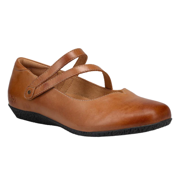 A TAOS Women's Banter Caramel leather flat in brown with two crossing straps, arch support, and a black textured sole, shown from the side and slightly above on a white background.