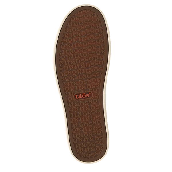 The TAOS Women's Z Soul Daisy Black features a brown sole with "taös" embossed in a pattern for arch support. An orange TAOS logo is centered, and the sole is shown from above, highlighting the canvas sneaker's full tread design.
