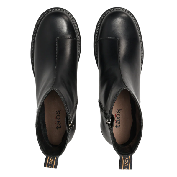 Top view of TAOS Women's Uptown Black ankle boots in leather, featuring side zippers, back pull tabs, cushioned insoles with arch support, and the taös logo.