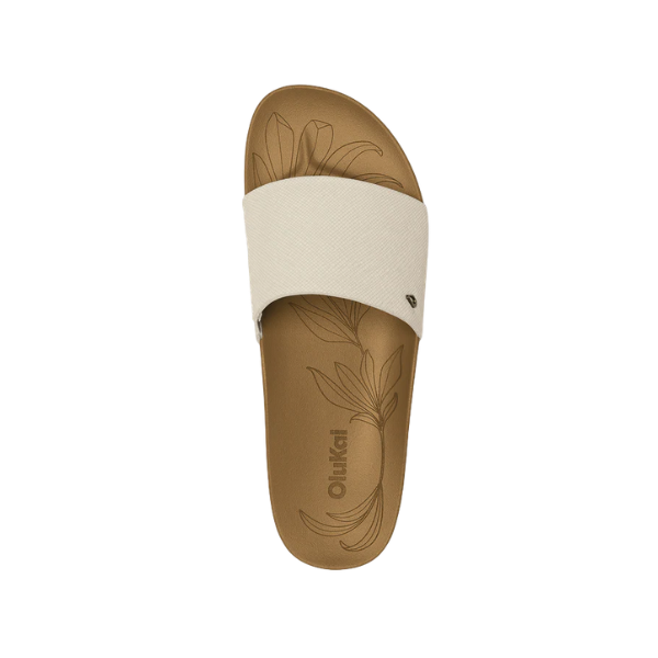 Top view of one OLUKAI Women's Kipea Pono Tapa slide sandal with a floral pattern on its contoured tan footbed.