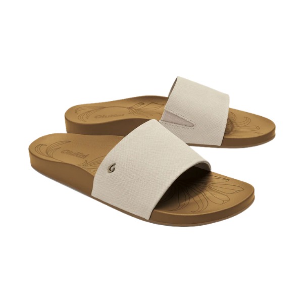 OLUKAI Women's Kipea Pono Tapa tan slide sandals with leaf-patterned, contoured footbed on a white background.
