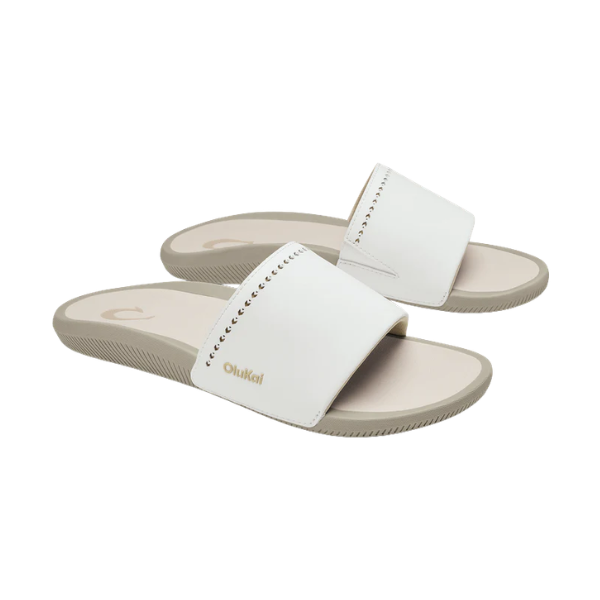 OLUKAI Women's Ulele Slide White sandals with white straps, gold logo, and supportive footbed.