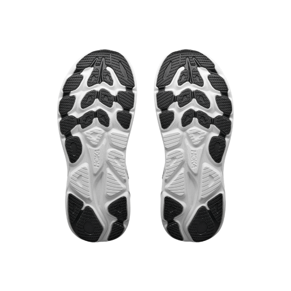 The soles of HOKA Women's Clifton 11 Black/White running shoes feature textured grips, shown from the bottom.