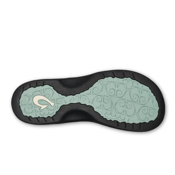 The image shows the sole of the OLUKAI Olukai Womens Ohana Mint / Swell Hua sandal with a black outer edge, a light blue-green wavy center, and a white curved logo on the heel of its non-marking rubber outsole.