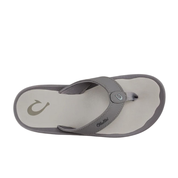 The OLUKAI Mens Ohana Graphite sandal, shown in gray and beige with a logo on the footbed and strap, features a fabric toe post, anatomical footbed for comfort, and water-resistant design—all displayed against a white background.