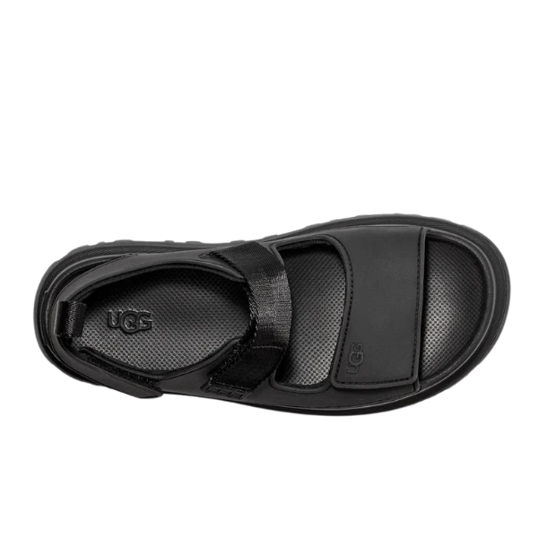 Top view of UGG Womens Goldenglow Sandals in black, featuring an open toe, adjustable Velcro strap, textured insole, and visible UGG logo on the insole and side near the toes.