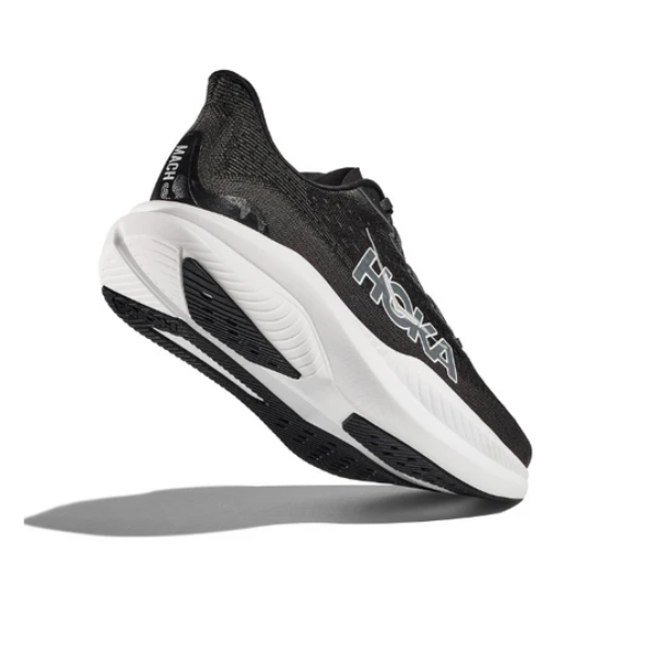 The HOKA Men’s Mach 6 (Wide Width) in Black/White, shown angled upward with a thick cushioned sole and side HOKA logo, is designed for speed and everyday running. Displayed on a plain white background with a shadow beneath.
