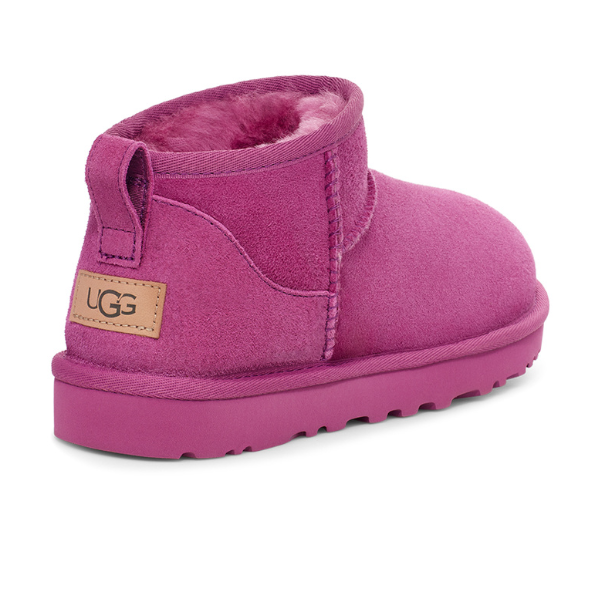 The UGG Womens Classic Ultra Mini Boot Purple features a suede exterior, plush lining, thick rubber sole, low ankle design, and a tan UGG logo label on the back.